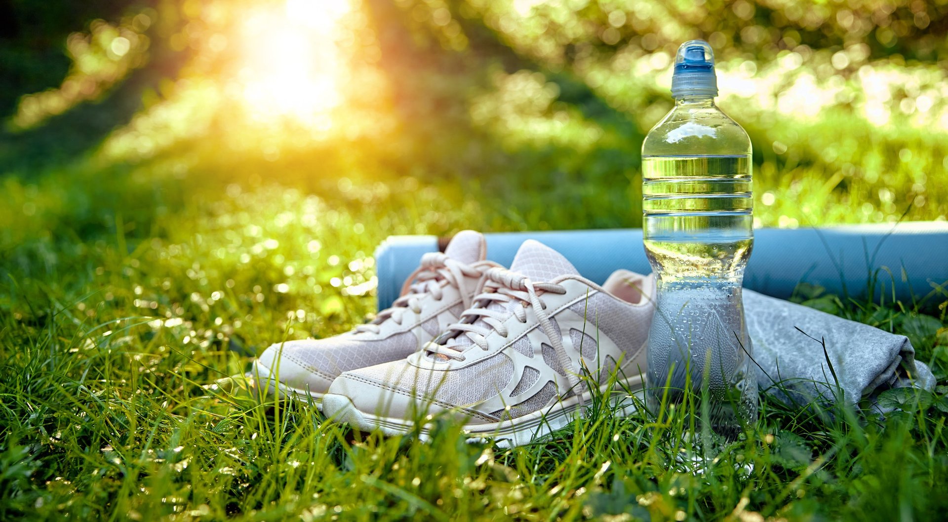 Running shoes water bottle yoga mat on grass