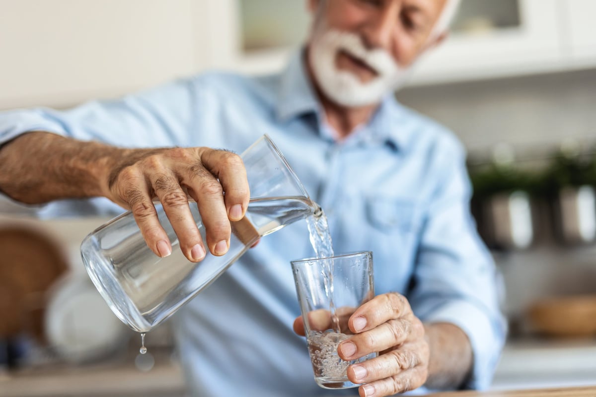 Person pouring water into a glass during daily routine at home