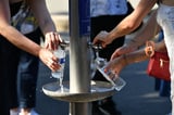 Person filling water bottle at public fountain