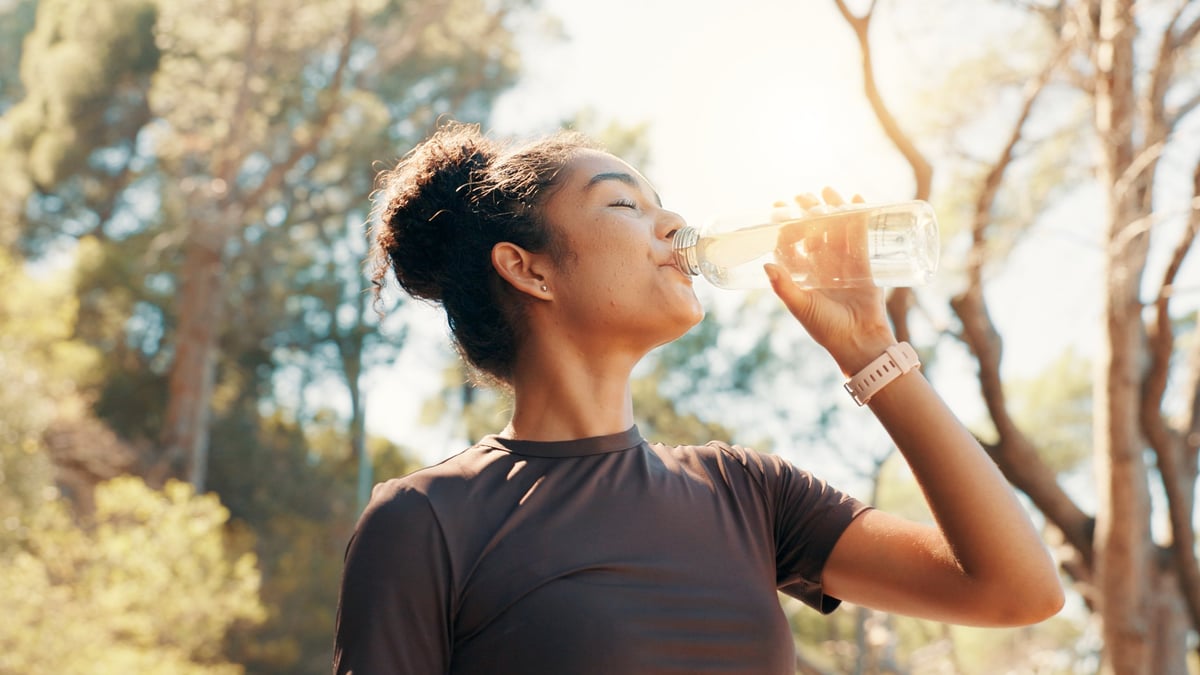 Woman, drinking water and fitness in nature for hydration, electrolytes and body detox